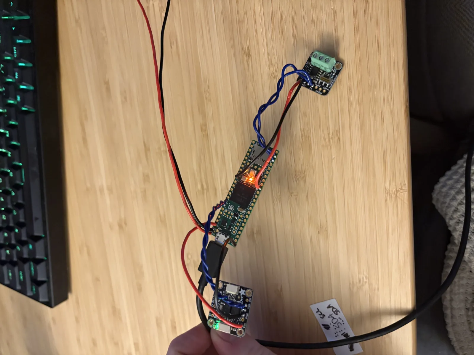A Teensy 4.1, a BNO085 IMU breakout, and a CAN transceiver breakout wired together loose on a desk, with the Teensy power LED lit.