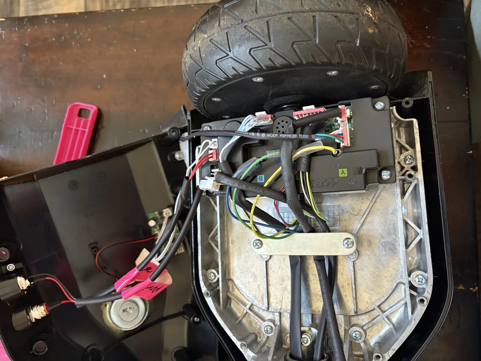 A hoverboard with the shell opened, showing the hub motor, factory controller board, and phase wiring.